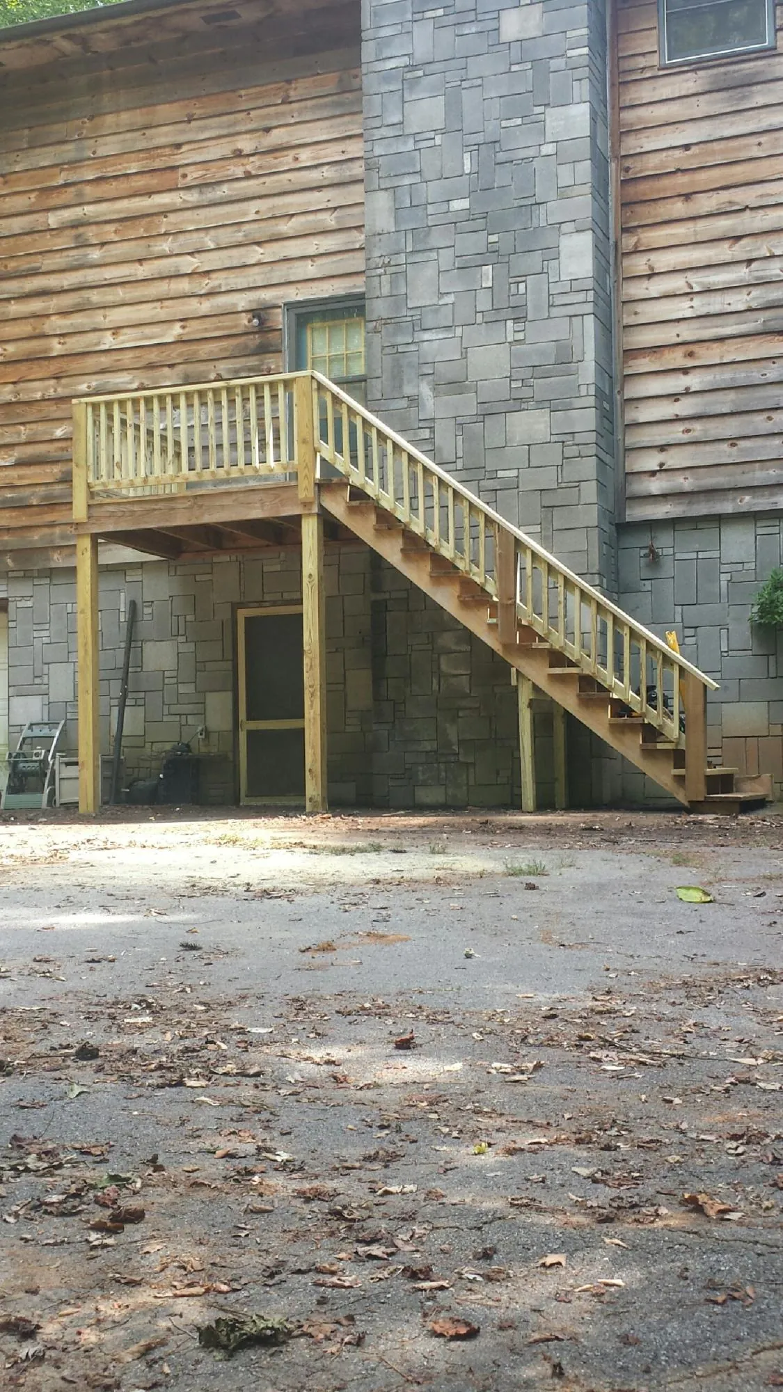 New pressure treated deck and stair landing on a log home in Jamestown